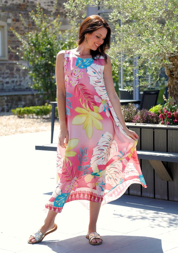 Woman wearing a colorful floral dress standing outdoors.