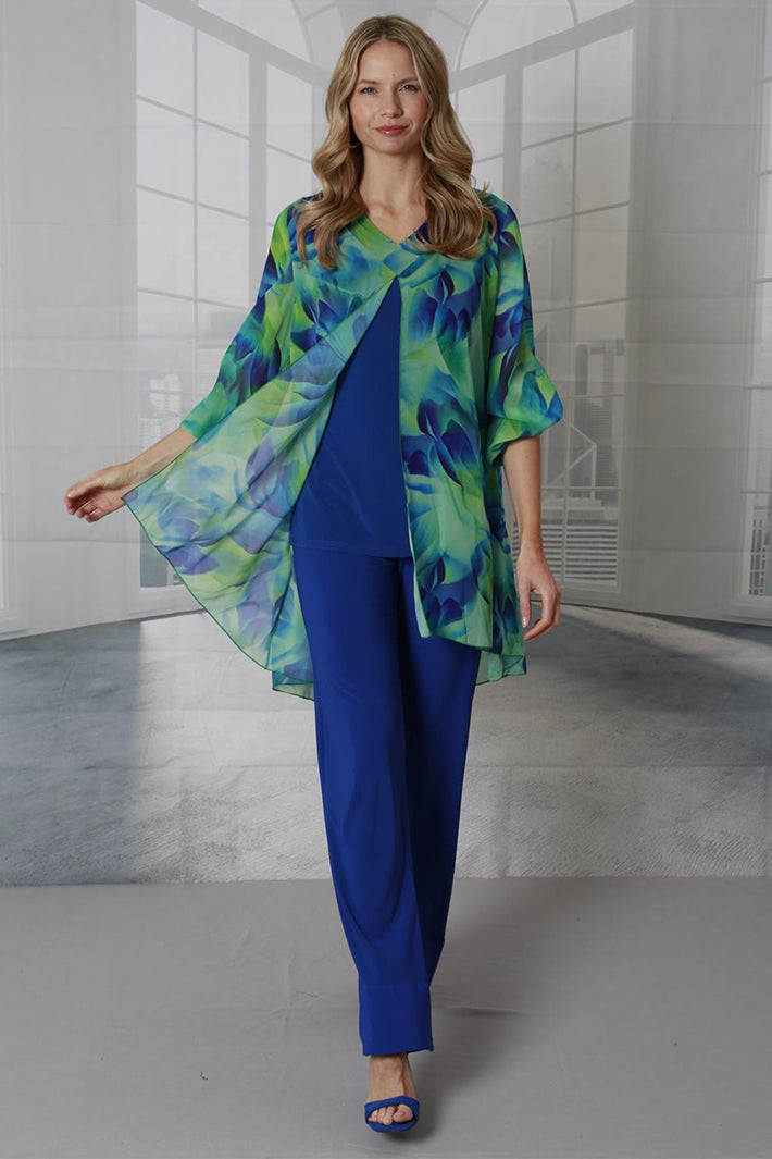 Woman wearing a blue outfit with a green and blue patterned top in an indoor setting.