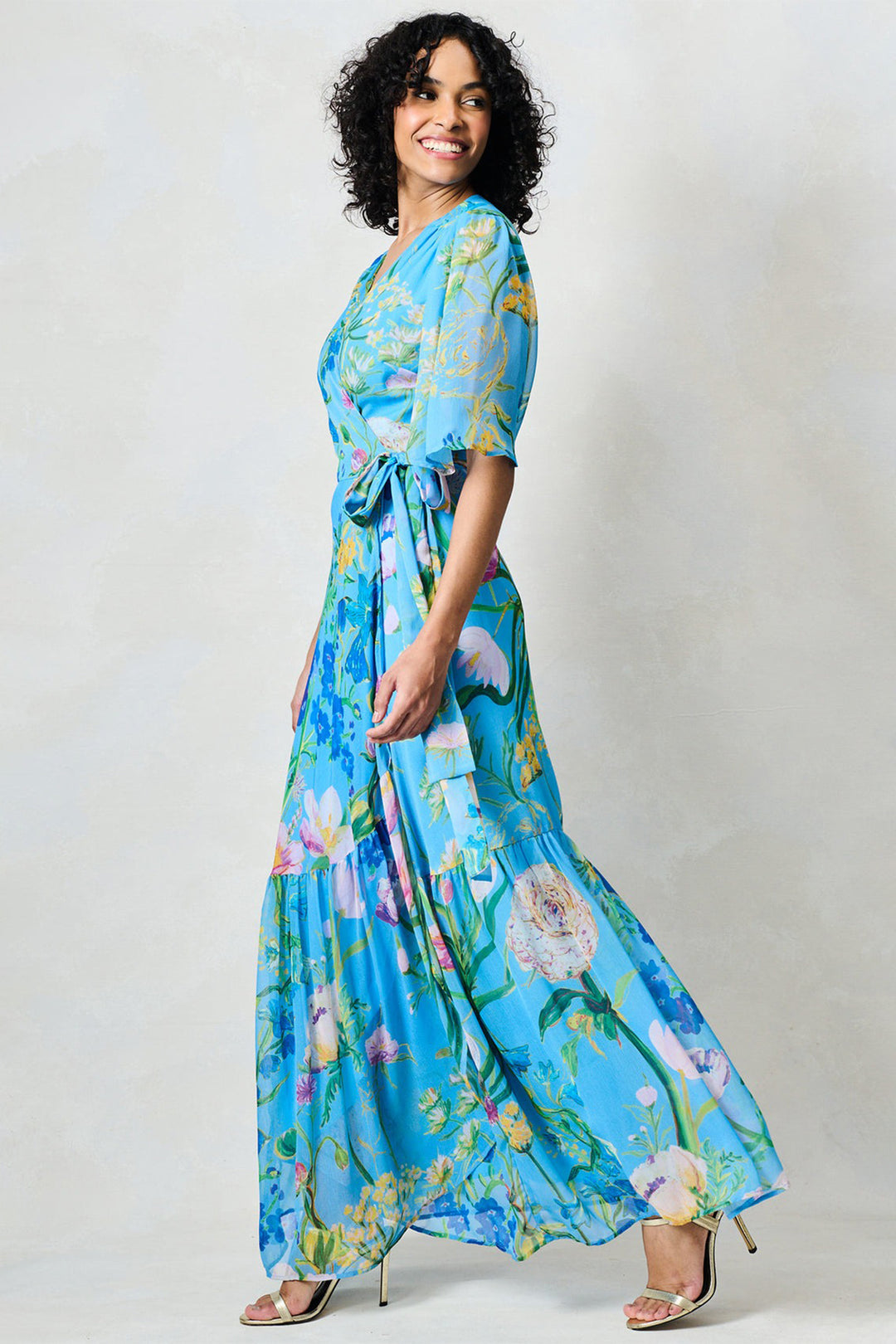 Woman wearing a blue floral dress against a plain background