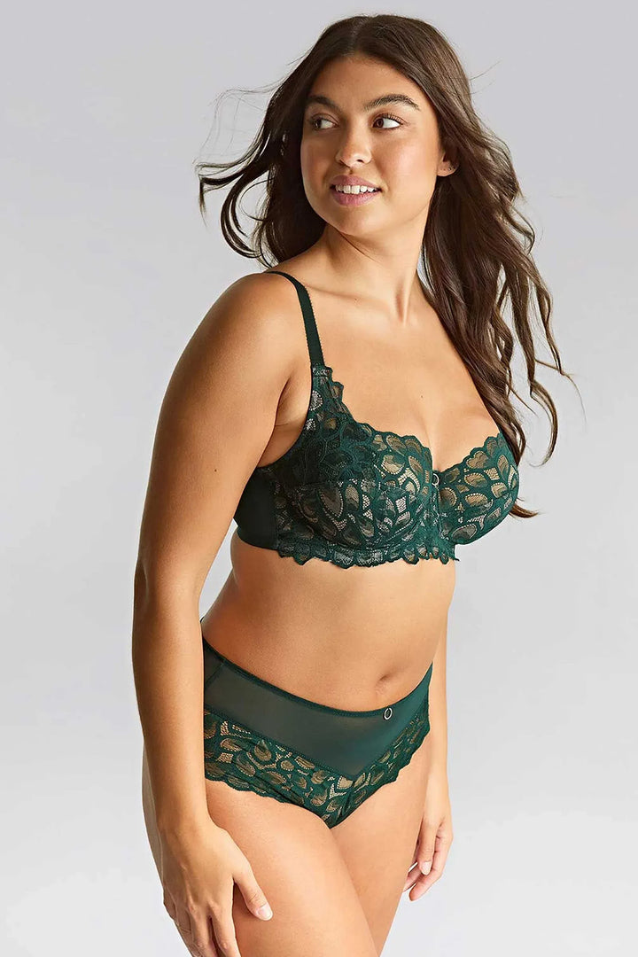 Woman wearing a green lace lingerie set against a plain background