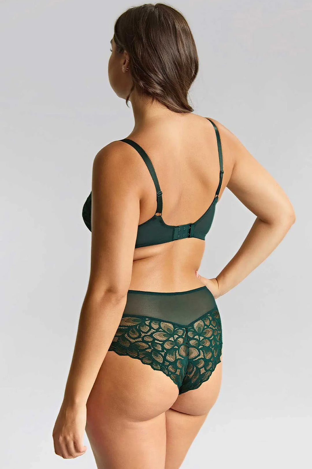 Woman wearing a green lace lingerie set on a plain background