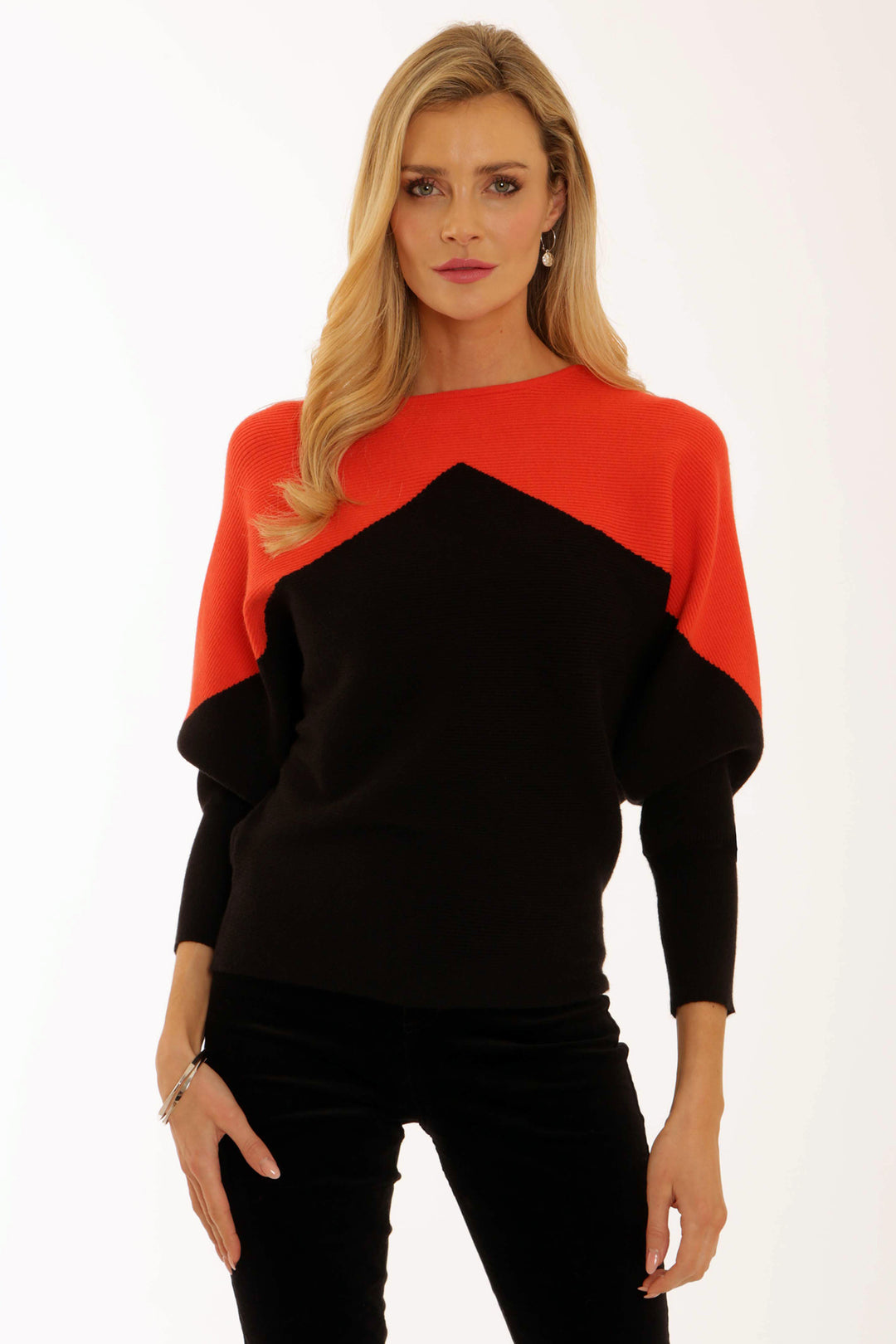 A woman wearing a black and orange colour-blocked sweater on a white background