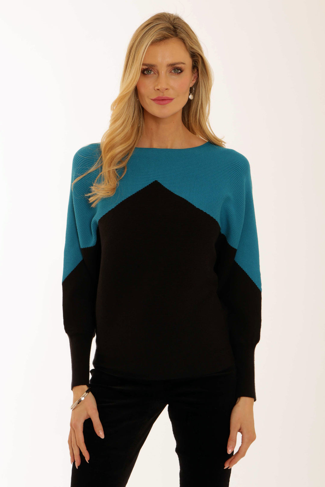Woman wearing a black and teal colour-blocked sweater on a white background